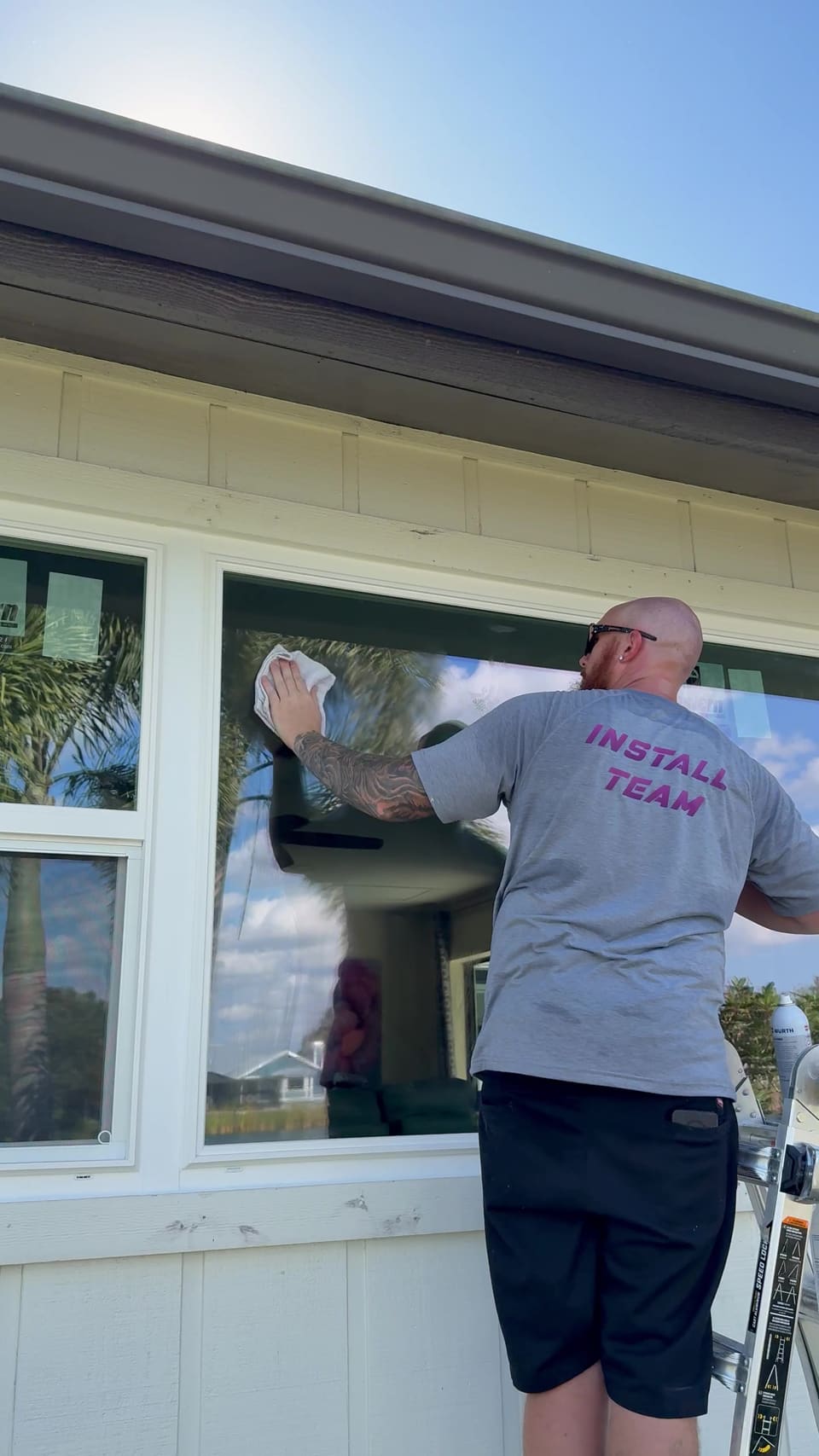 Three Brothers install team cleaning a new window from a ladder