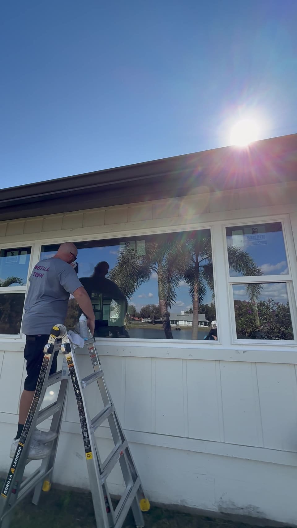 Installer on a ladder sealing a new window from outside
