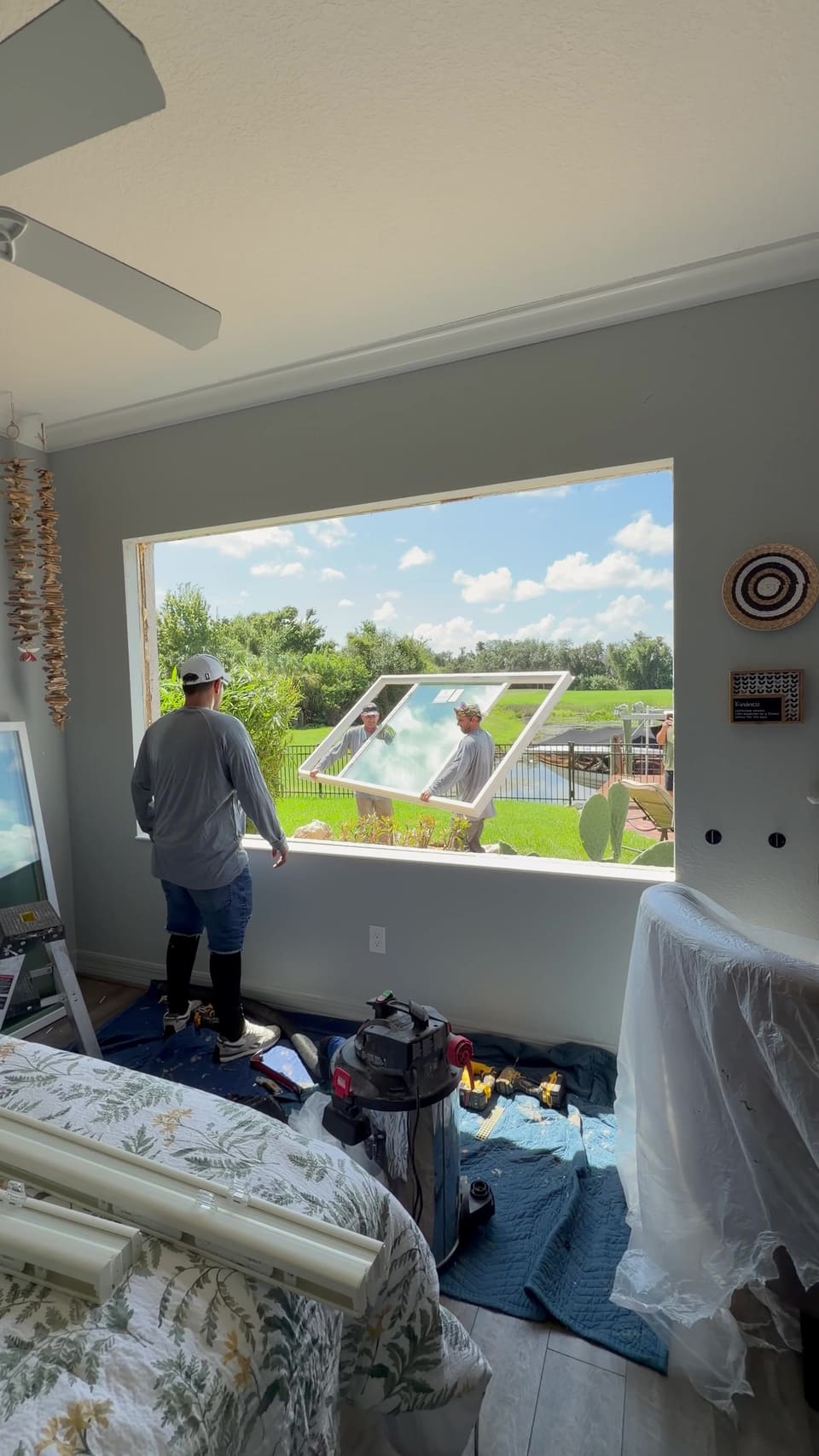 Crew setting a new picture window into a bedroom opening, with the room covered